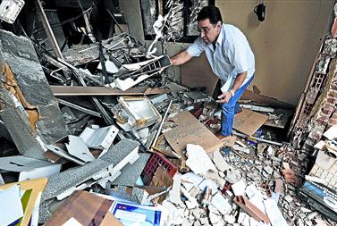 Un hombre recoge objetos entre los escombros de la destrozada sede socialista de Durango. Foto: AP / ÃVARO BARRIENTOS