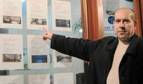 El empresario muestra los rótulos de su agencia inmobiliaria El empresario muestra los rótulos de su agencia inmobiliaria